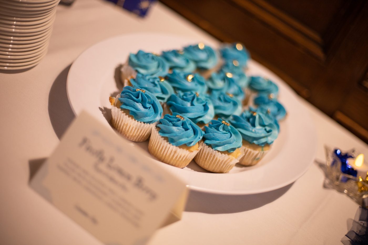Close-up of cupcakes with teal blue frosting swirls and gold dragées