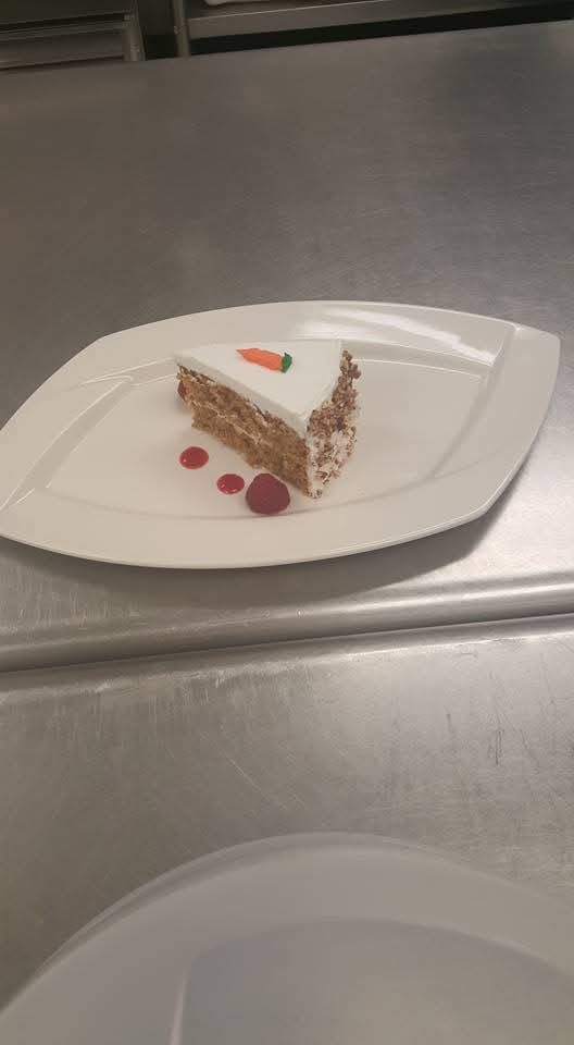 Slice of carrot cake with cream cheese frosting and a fondant carrot