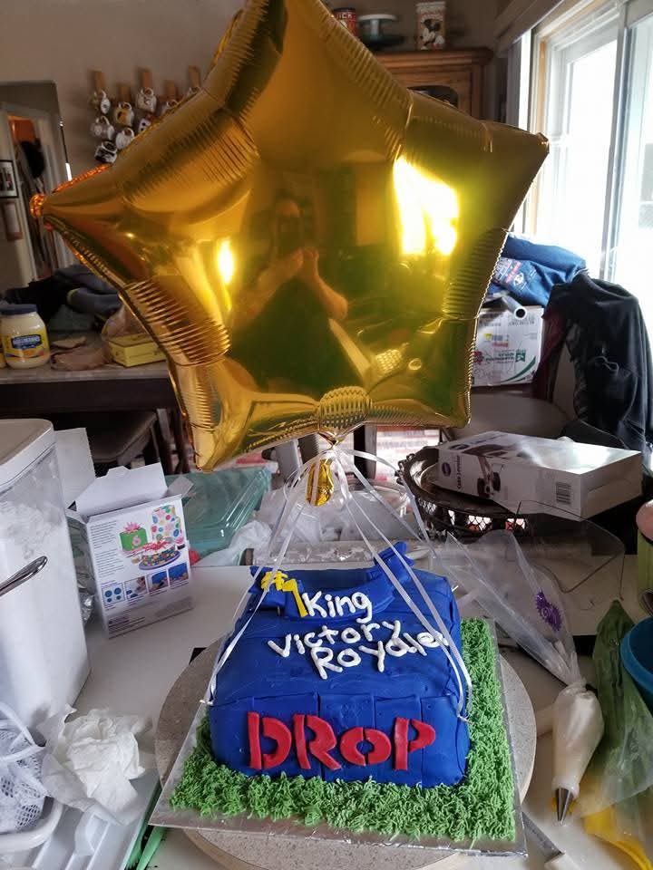 Blue battle-royale themed birthday cake with gold balloon