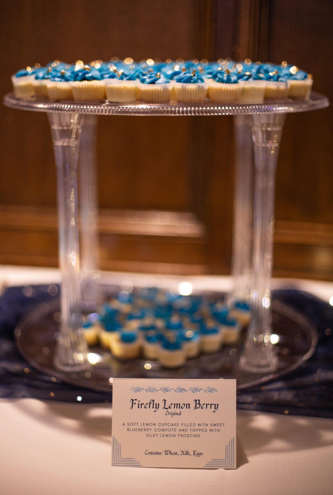 Firefly Lemon Berry cupcake display with description card on a glass stand
