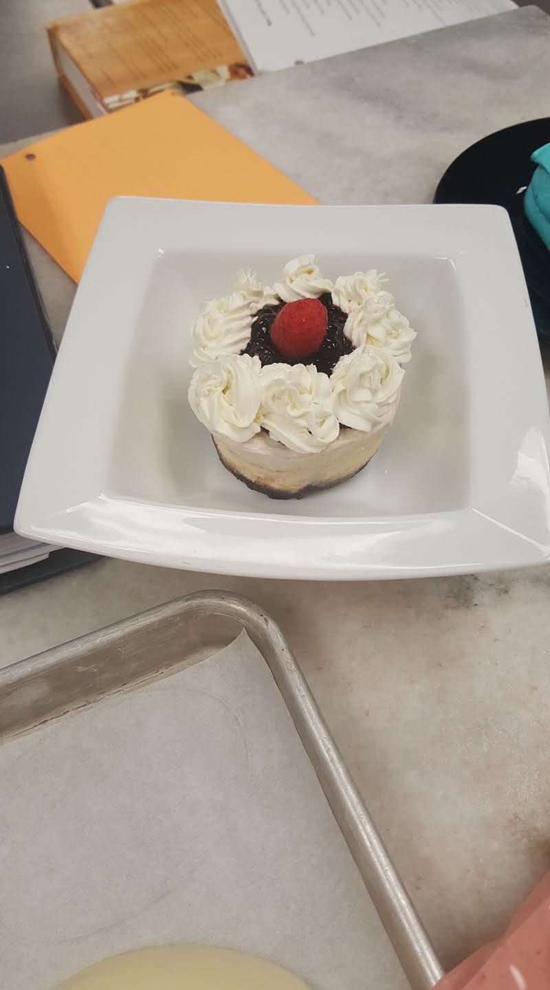 Mini cheesecake with whipped cream rosettes and a fresh raspberry